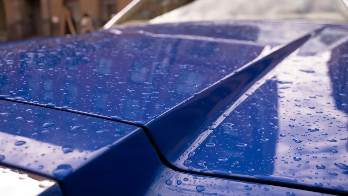 Water beading on a freshly ceramic-coated blue car hood